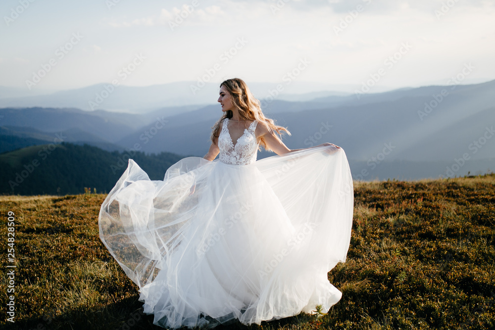 Stylish bride standing on beautiful landscape of mountains on sunset Stylish bride standing on beautiful landscape of mountains on sunset