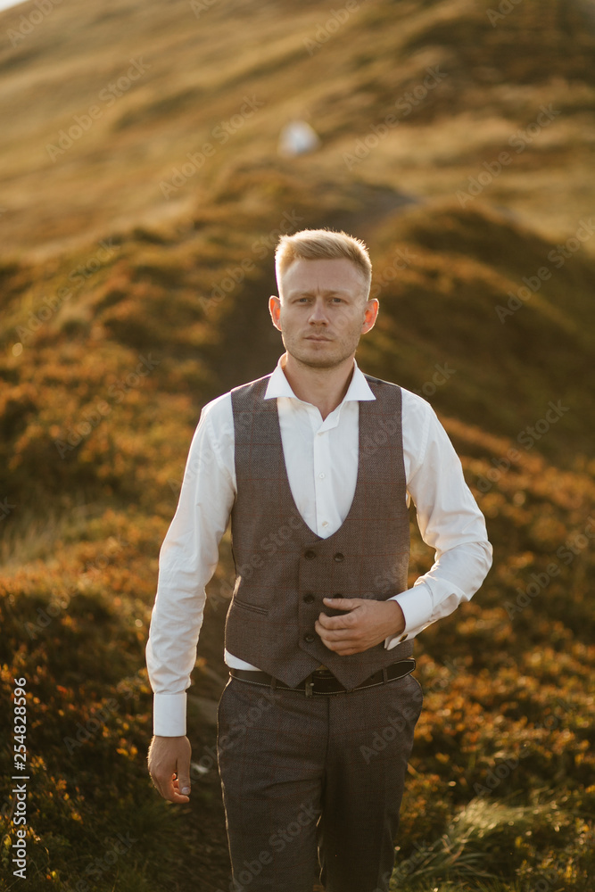 Obraz premium young man standing on a mountain at sunset