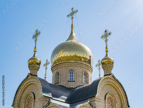 The domes of the Orthodox church against the blue sky, beautiful golden