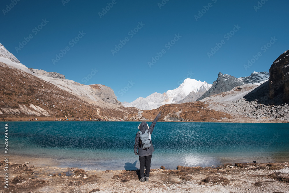 Tourist raise hand up with turquoise lake and mountain range on peak