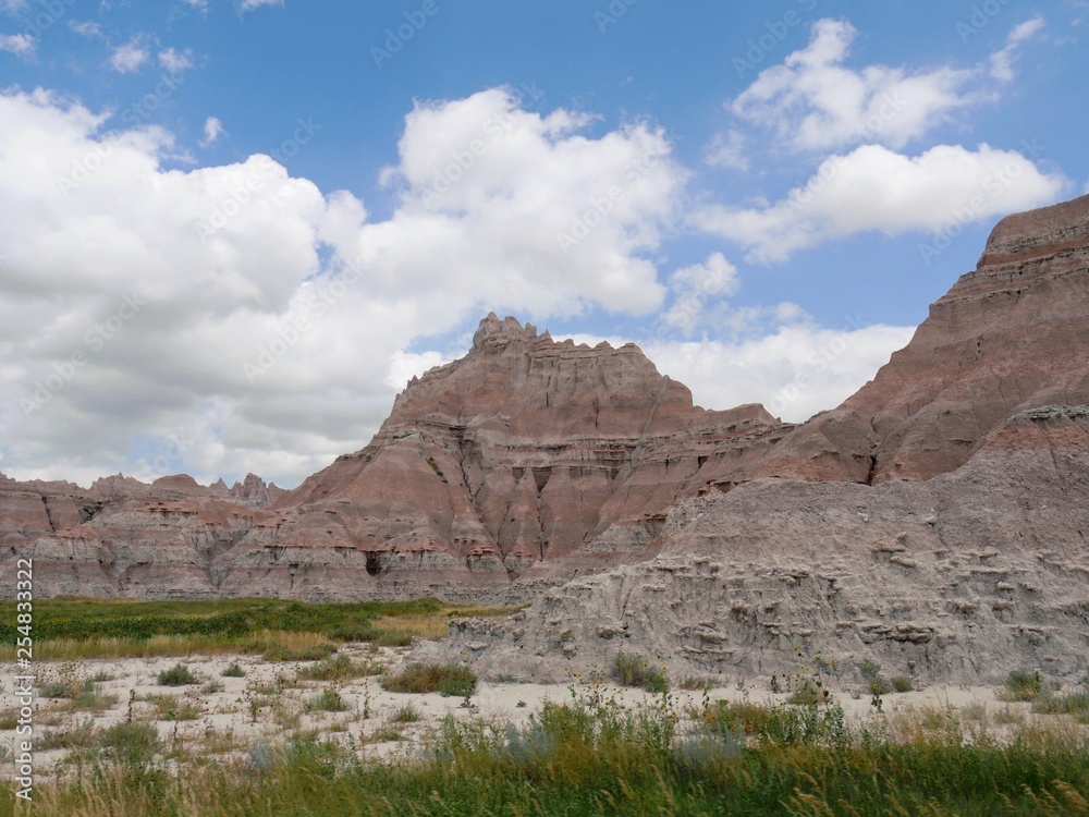 Fototapeta premium Wide view of buttes and rock formations with beautiful clouds at the Badlands National Park in South Dakota.