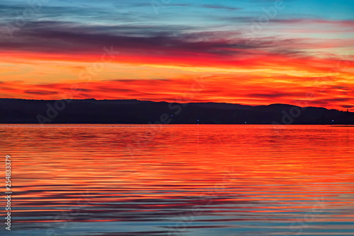 Stunning colorful red sunset at the sea with dramatic clouds