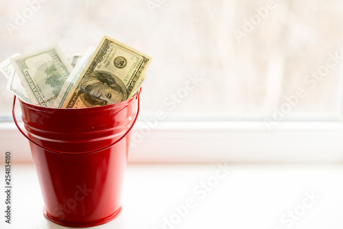 Dollar bills in red pail. on white window.light background. place for text. top view. a lot of money photo