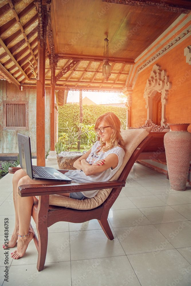 Obraz premium Girl using laptop on a home porch / terrace.
