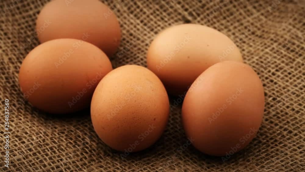 Five fresh brown chicken eggs rotating on burlap fabric background Five fresh brown chicken eggs rotating on burlap fabric background