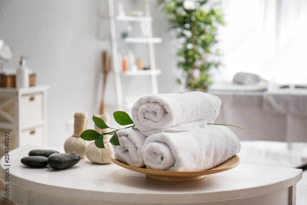 Towels, massage stones and herbal bags on table in spa salon