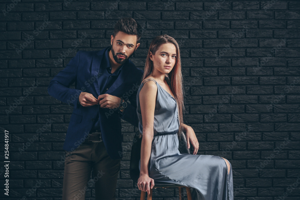 Fashionable young couple near dark brick wall