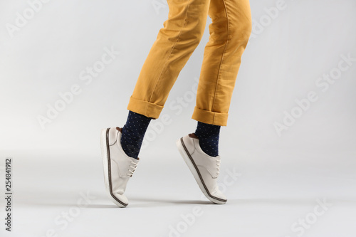 Legs of fashionable young man on light background