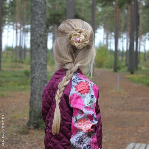 A little girl with a braided hairdo in a forest