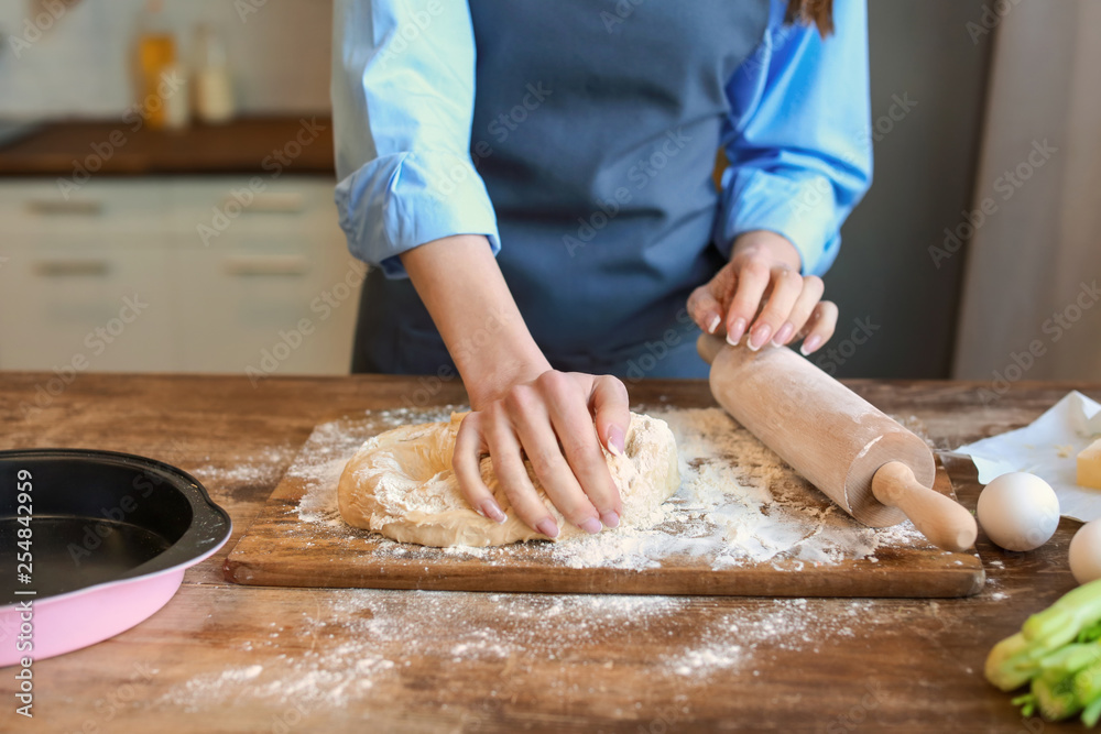 Beautiful woman making dough in kitchen at home