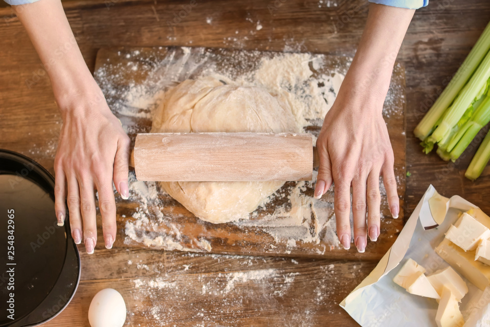 Woman making dough on wooden table