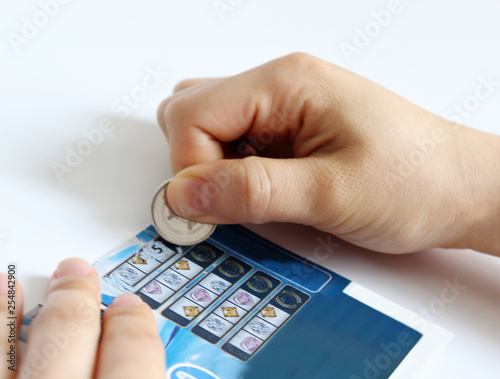 A woman's hand scratching an instant lottery ticket with a coin. photo