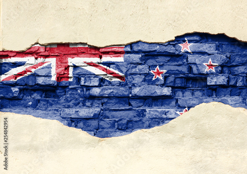 National flag of New Zealand on a brick background. Brick wall with partially destroyed plaster, background or texture.