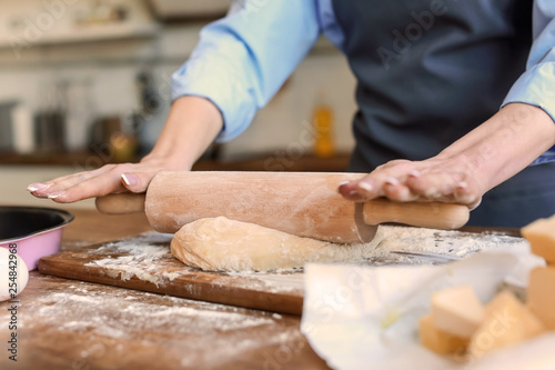 Beautiful woman making dough in kitchen at home, closeup