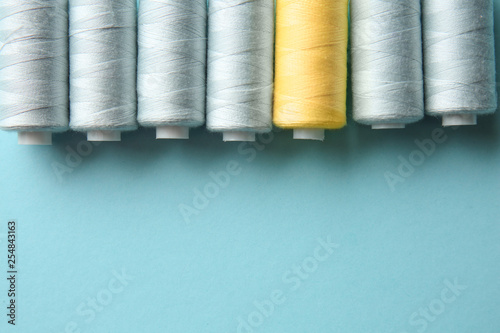 Yellow threads among grey ones on color background. Concept of uniqueness