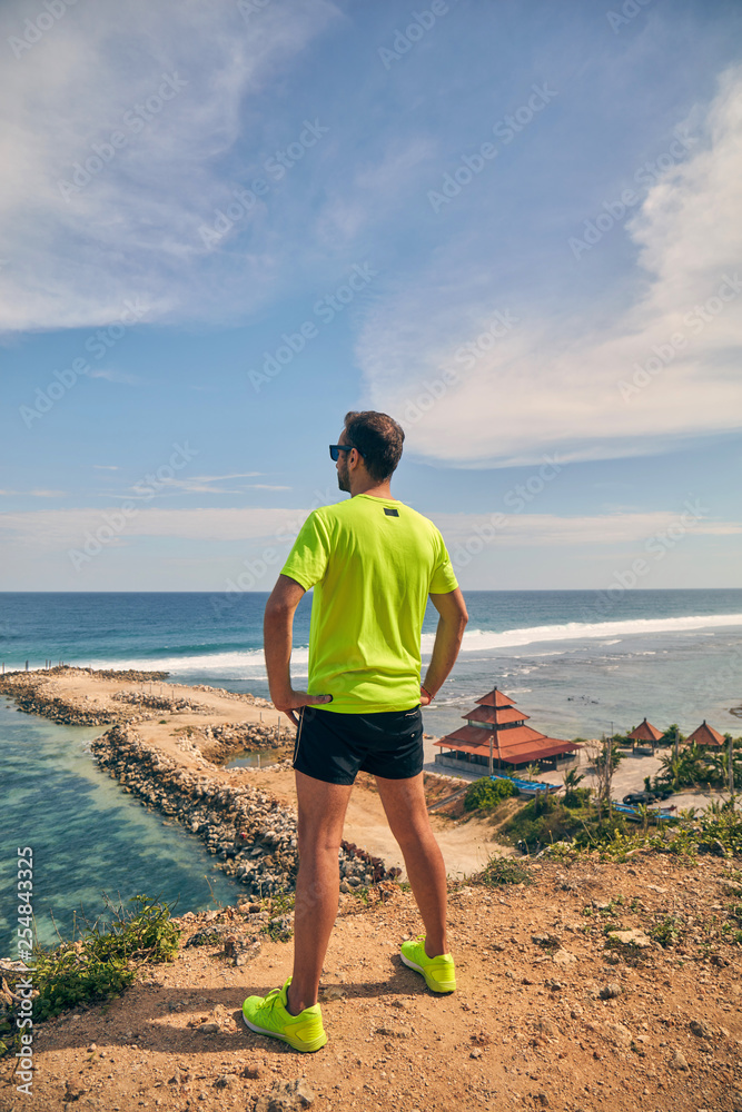 Sportsman on a tropical exotic cliff near the ocean.