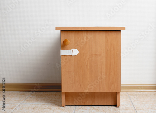 Bedside table wooden with baby proofing cabinet lock at home child safety photo