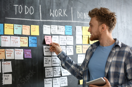 Young man near scrum task board in office photo