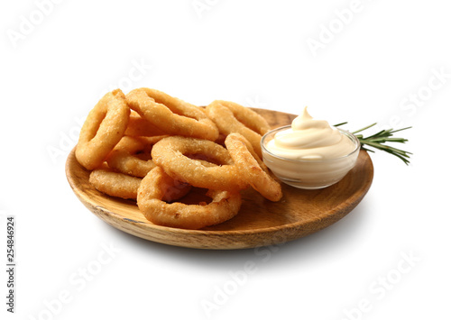 Plate with tasty onion rings and sauce on white background