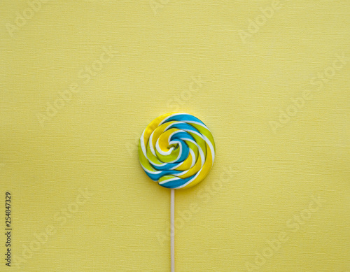 Blue yellow lollypop on yellow background