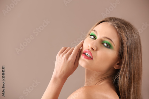 Beautiful young woman with bright makeup on color background