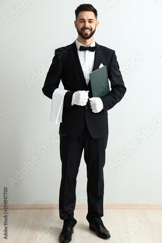Naklejka Handsome waiter near light wall