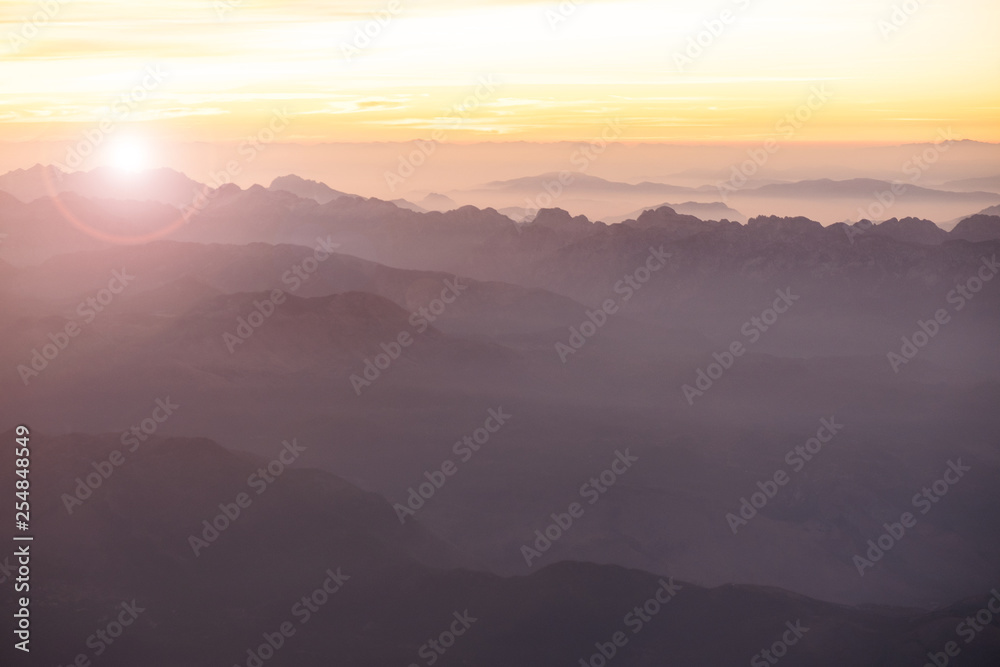Foggy morning in Italian Alps mountains. Mountain range silhouttes aerial view.