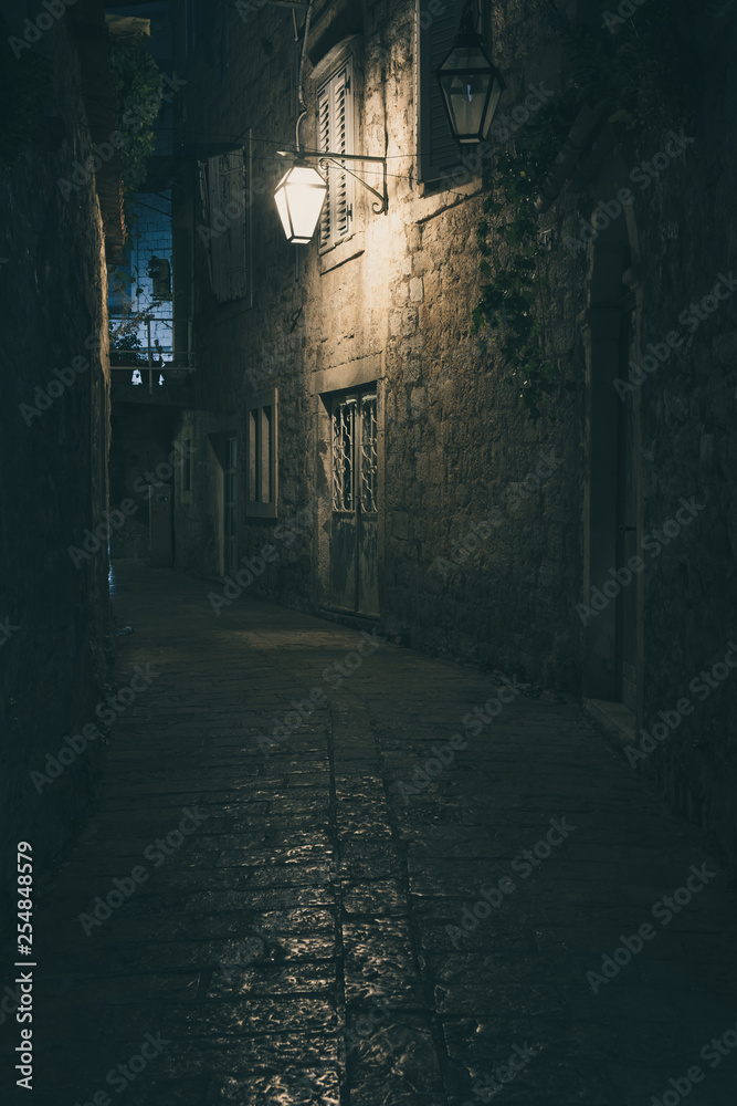 Old street at night illuminated by vintage streetlight.