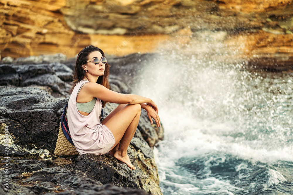 Pretty long hair brunette tourist girl relaxing on the stones near sea. Pretty long hair brunette tourist girl relaxing on the stones near sea.