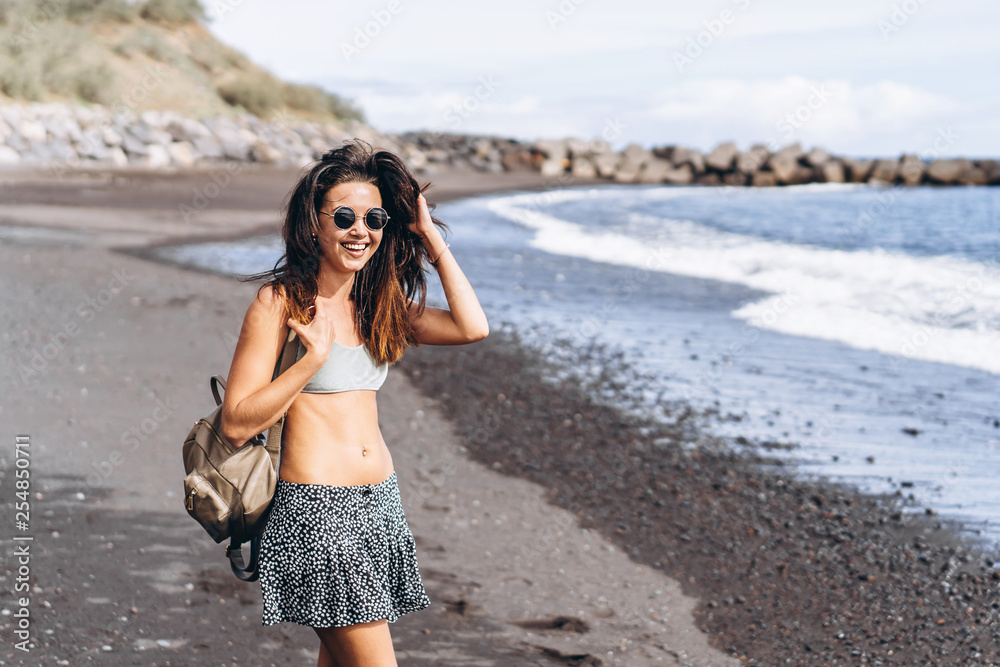 Pretty brunette long hair girl have fun on the beach with black sand near sea. Pretty brunette long hair girl have fun on the beach with black sand near sea.