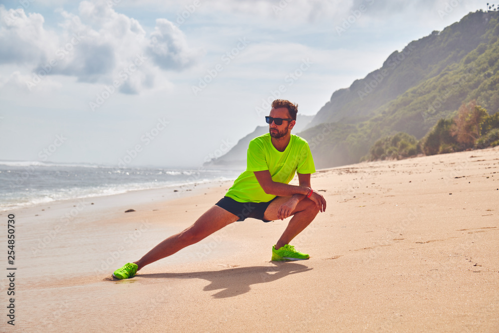 Sportsman stretching on a tropical sandy beach. Sportsman stretching on a tropical sandy beach.