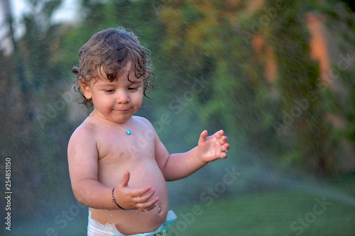 Quadro em tela Baby getting wet on a garden in summer