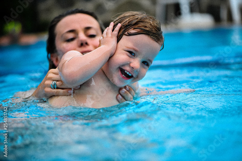 Baby plays in a pool with his Mom