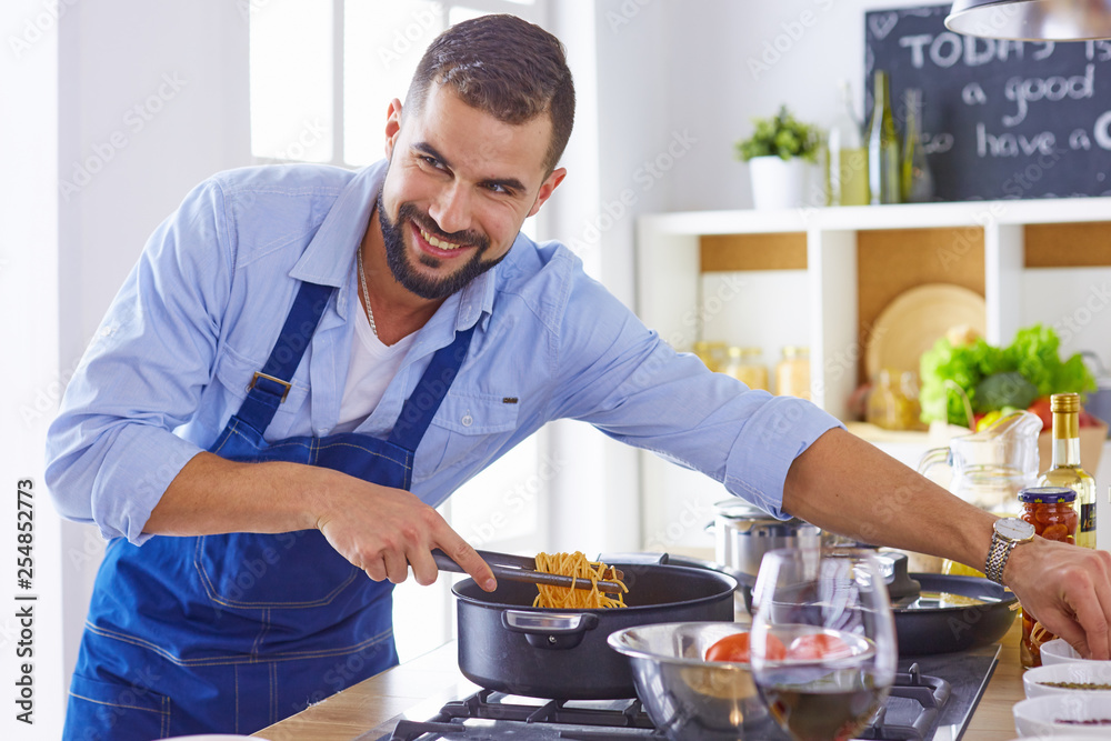 Smiling and confident chef standing in large kitchen Smiling and confident chef standing in large kitchen
