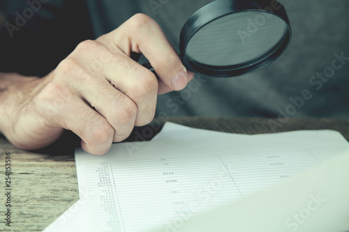 Man hands looking document with magnifying glass