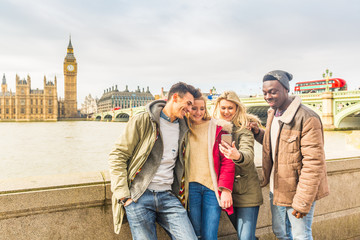 Happy multiracial friends group using smartphone in London