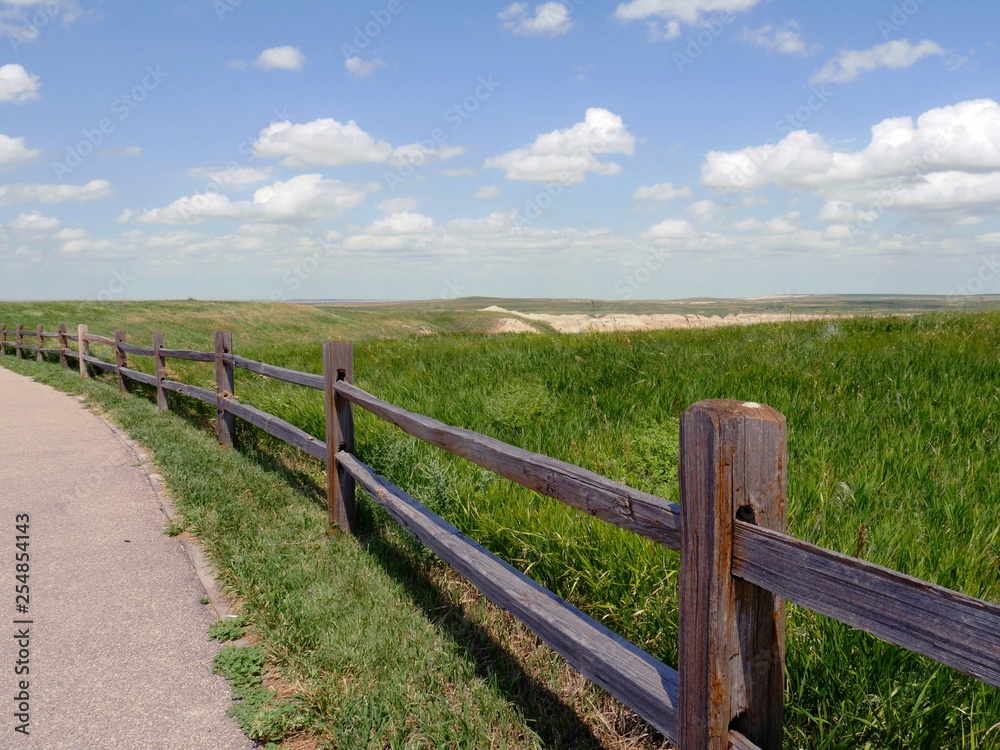 Wooden fence running along the paved road at Badlands National Park in South Dakota.