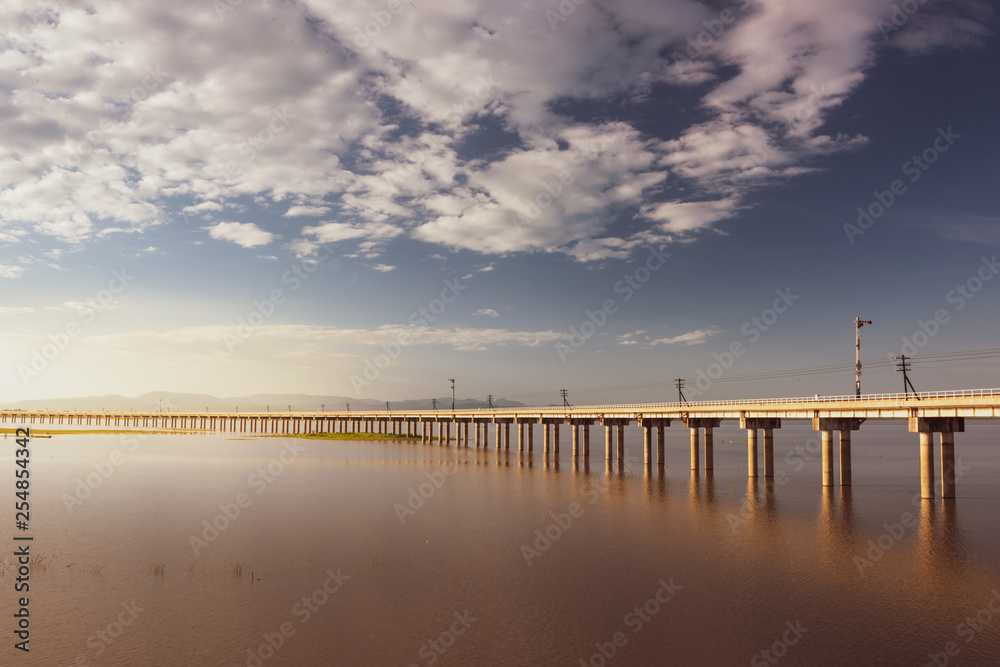 Obraz premium Landscape View of Train crossing Pasak Chonlasit Dam. Reservoir for agriculture at Lopburi,Thailand