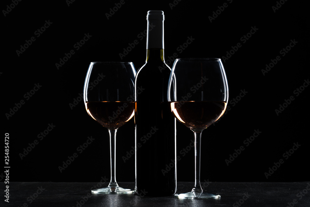 Bottles of wine and different glasses of wine on a dark background Bottles of wine and different glasses of wine on a dark background