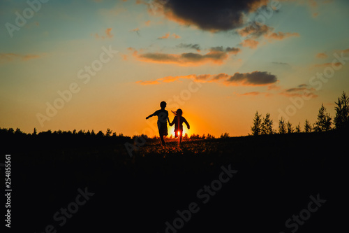 Silhouette of happy boy and girl running play at sunset © nadezhda1906