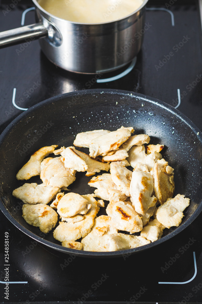 Food shot of cooking poultry meat slices on a black pan Food shot of cooking poultry meat slices on a black pan