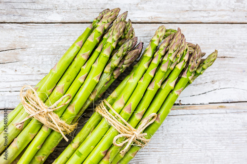 Fresh and raw green asparagus bunches on a wooden background. 