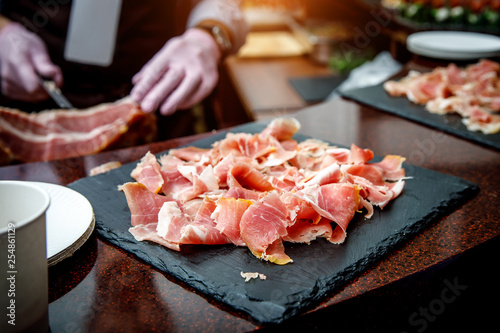 Сlose-up of thin slices of spanish jamonon black cutting board photo