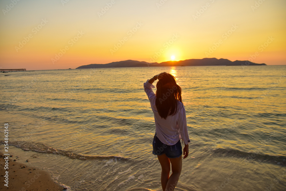 Women standing on beach at sea sunset background on evening golden hour.Travel summer holiday sea beach in Thailand