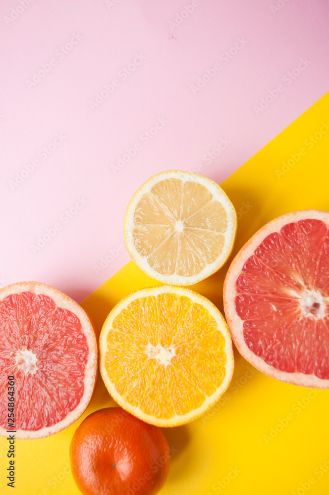 Flat lay of cut ripe juicy grapefruit, lemon and orange on yellow and pink background. Citrus pattern. Flat lay of cut ripe juicy grapefruit, lemon and orange on yellow and pink background. Citrus pattern.