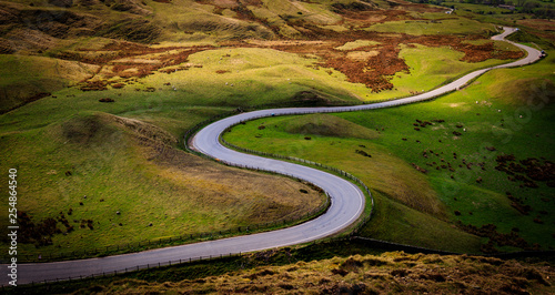 Sheep at Mam Tor, Peak District National Park, with a view along the winding road among the green hills down to Hope Valley, in Derbyshire, England