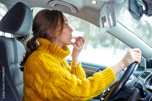 Young woman applying makeup in a car