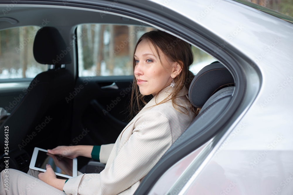 Attractive executive female manager working with a tablet in a backseat of a car