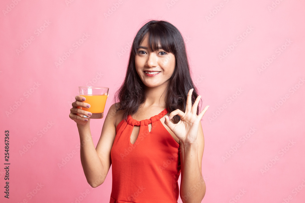 Young Asian woman drink orange juice show OK sign. Young Asian woman drink orange juice show OK sign.