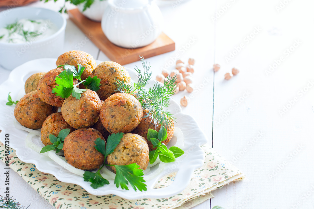 Chickpea falafel with fresh herbs on a white table, horizontal, copy space